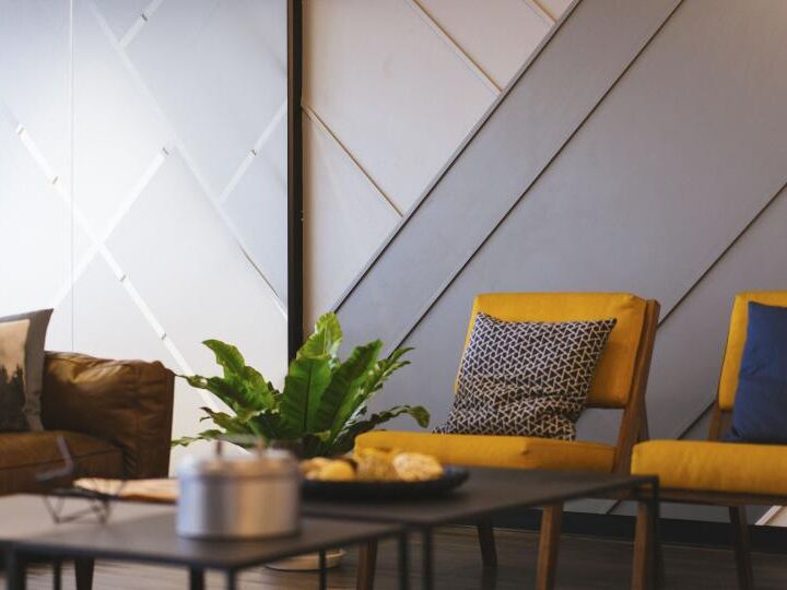 Sala de estar com poltronas amarelas, sofá de couro e parede com relevo