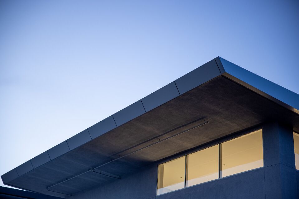 Casa de linhas retas com beiral escuro contra o céu azul