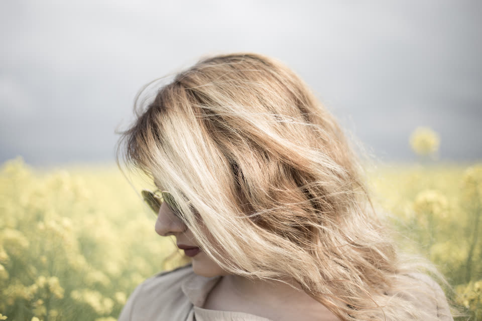 Retrato de mulher com cabelo ao vento num campo