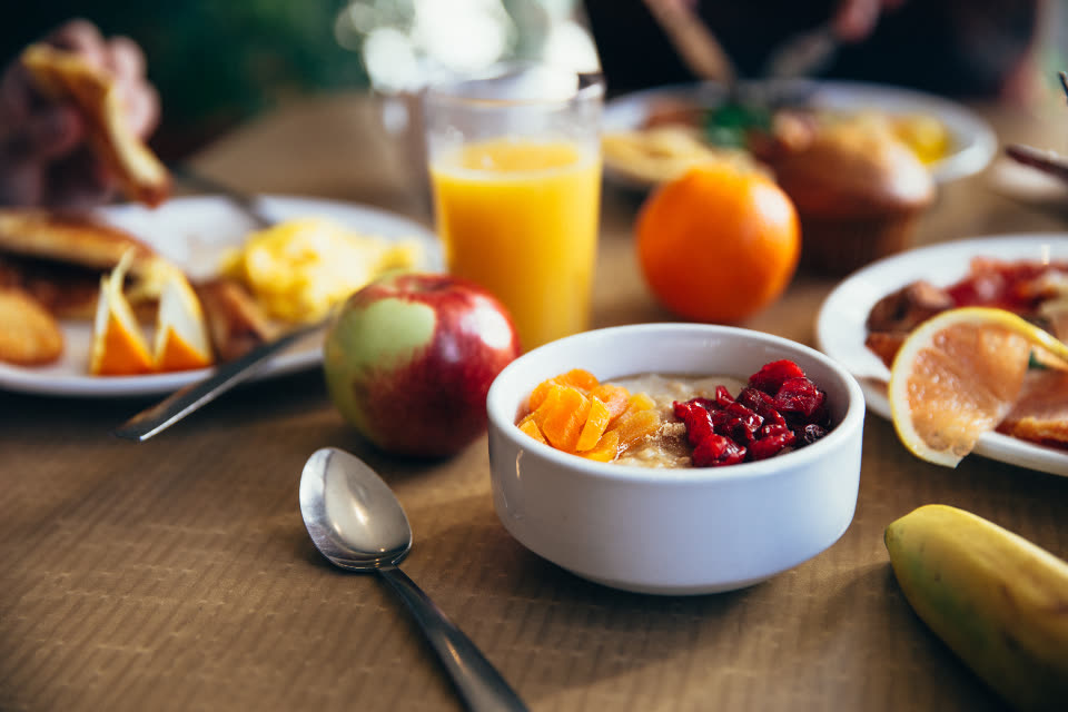 Mesa de café da manhã com frutas, suco e uma tigela de iogurte