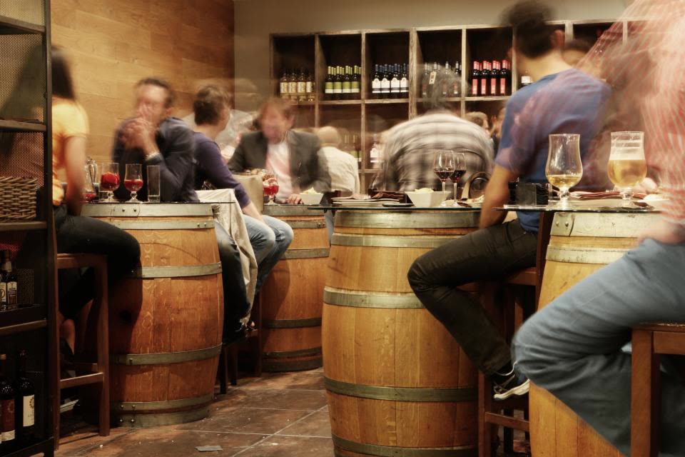 Clientes conversando no bar com barris de madeira