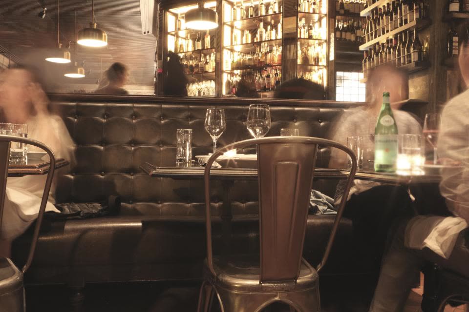 Salão do restaurante à noite, com mesas postas e luz baixa